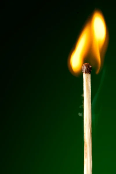 Brandende lucifer op groen — Stockfoto