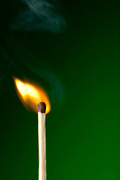 Brennendes Streichholz auf Grün — Stockfoto