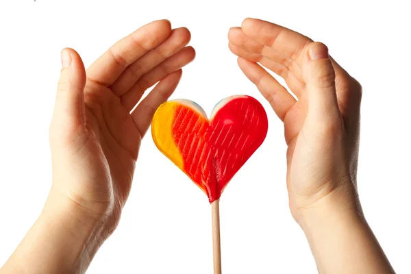 Hands surrounding lollipop heart — Stock Photo, Image