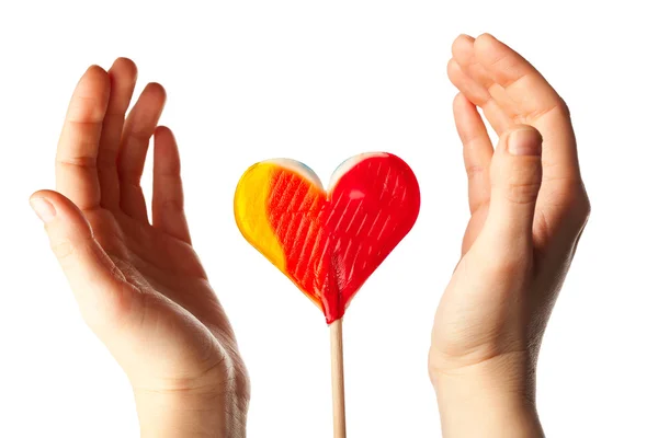 Händer kring lollipop hjärta — Stockfoto