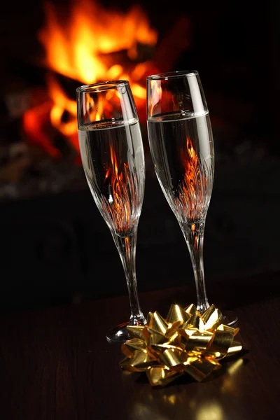 Бокалы с шампанским с золотым луком, огонь на заднем плане — стоковое фото