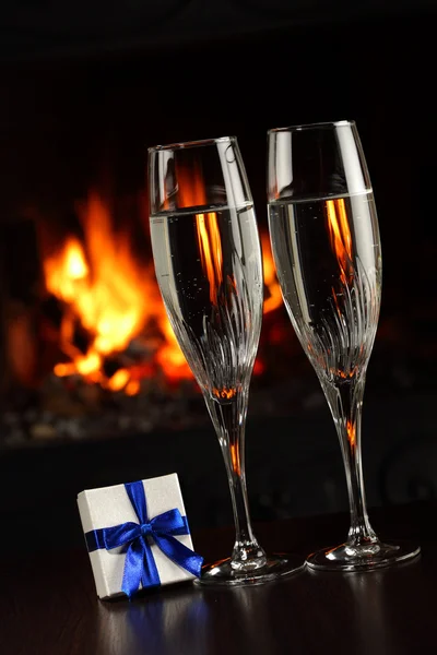 Brýle s šampaňským a dar, oheň jako pozadí — Stock fotografie