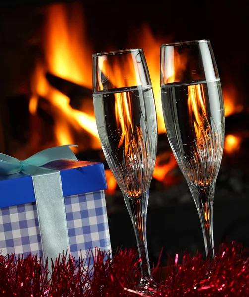 Бокалы с шампанским с рождественским антуражем, огонь на заднем плане — стоковое фото