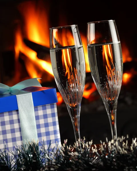 Brýle s šampaňským a dar, oheň jako pozadí — Stock fotografie