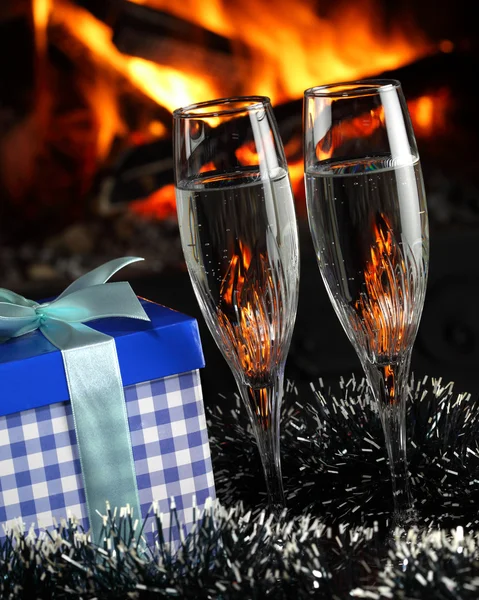 Okulary z szampana i prezent, ogień w tle — Zdjęcie stockowe