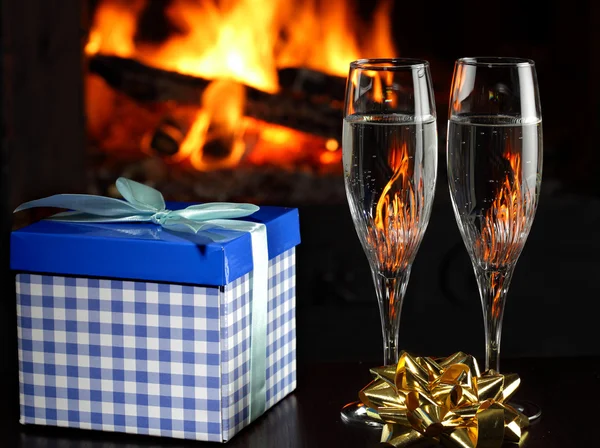 Bicchieri con champagne e un regalo, fuoco come sfondo — Foto Stock