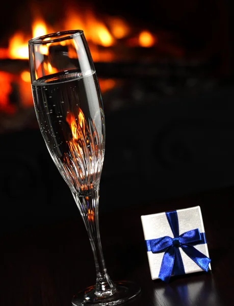 Copas con champán y un regalo, fuego como fondo — Foto de Stock