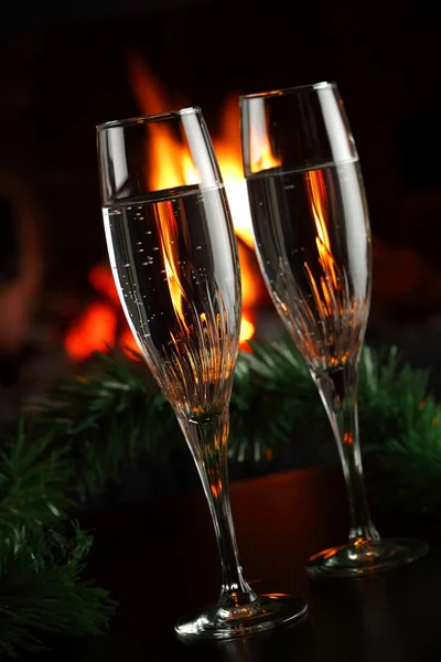 Glasses with champagne with christmas entourage, fire as the background — Stock Photo, Image