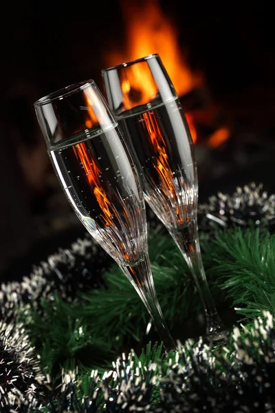 Glazen met champagne met kerst entourage, vuur als achtergrond — Stockfoto