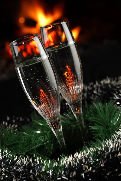 Glasses with champagne with christmas entourage, fire as the background — Stock Photo, Image