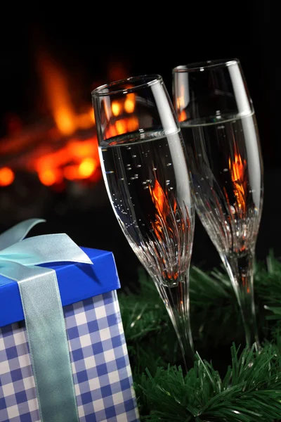 Verres avec champagne avec entourage de Noël, le feu comme arrière-plan — Photo