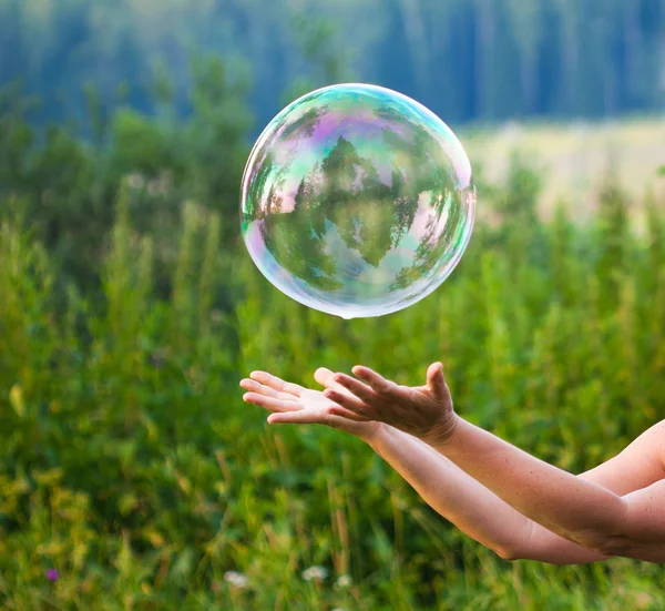 Hand catching a soap bubble — Stock Photo, Image