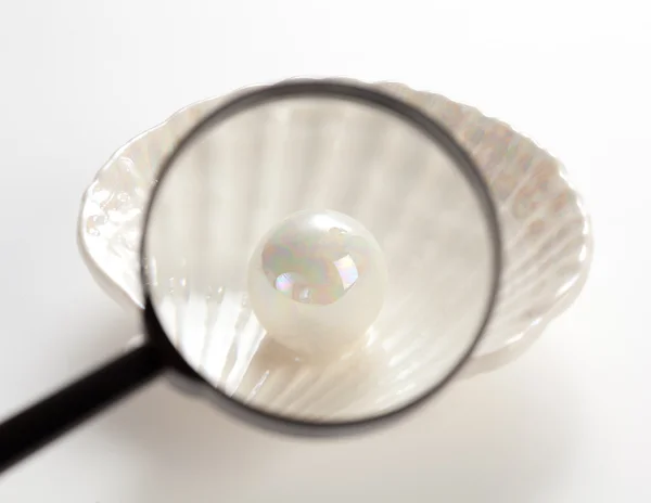Pearl under magnifying glass — Stock Photo, Image