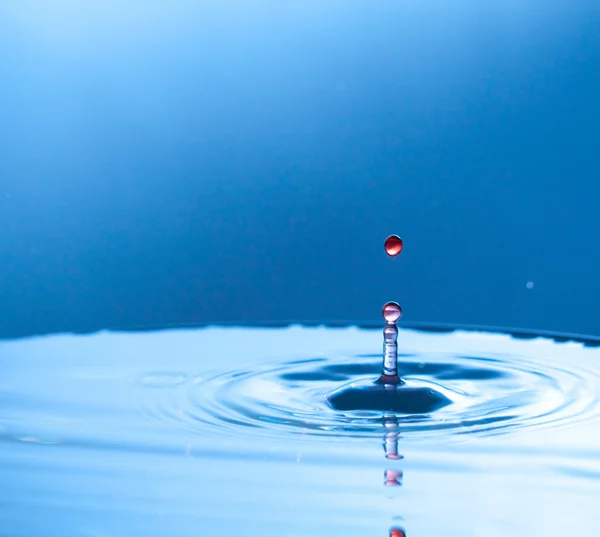 Red water drop on blue — Stock Photo, Image