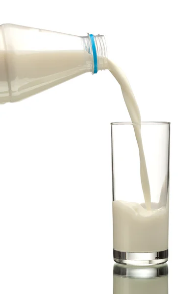 Milk flowing from bottle to the glass — Stok fotoğraf