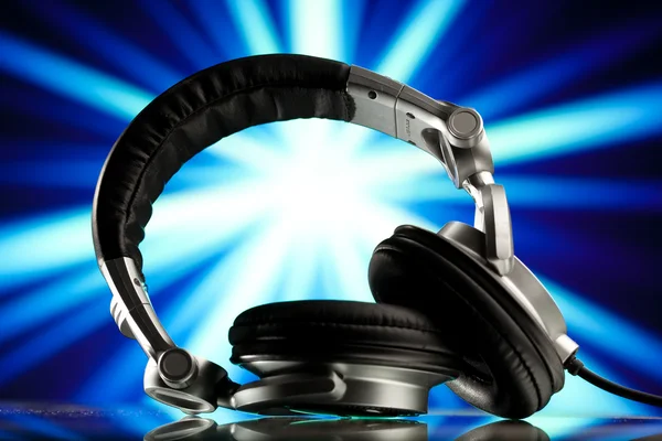 Headphones against blue rays background — Stock Photo, Image