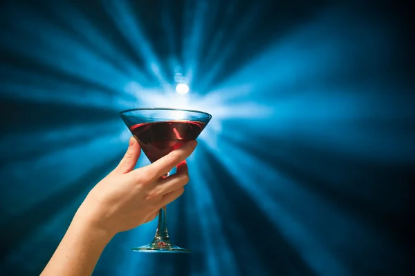 Hand som håller en cocktail mot blå bakgrund — Stockfoto