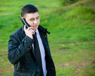 Man on mobile phone on natural green background clipart