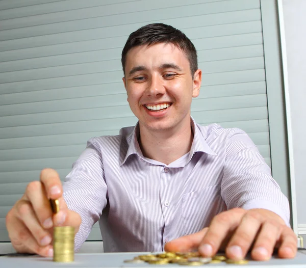 Бизнесмен кладет монеты в колонны — стоковое фото