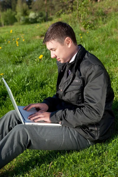 stock image Man with a laptop on the grass