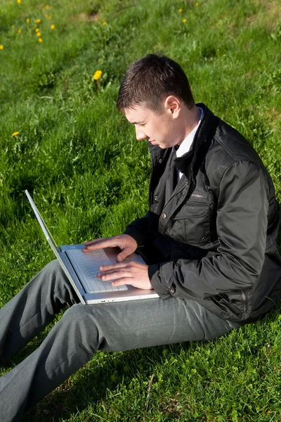 stock image Man with a laptop on the grass