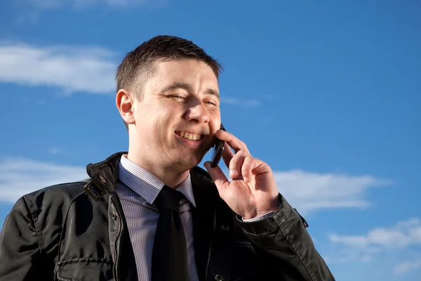 Człowiek na telefon komórkowy na naturalny niebieski tło — Zdjęcie stockowe