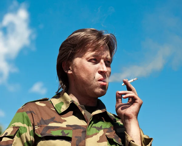 Smoking soldier against the sky background — Stock Photo, Image