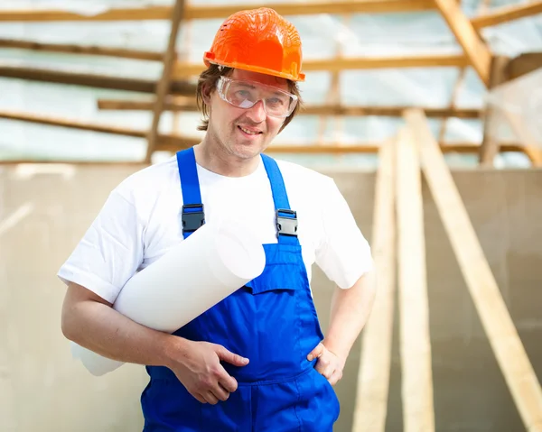 Smiling builder holding construction plan — Stock Photo, Image