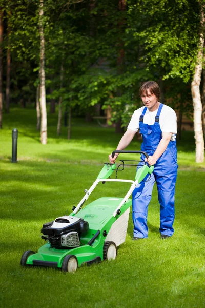 Césped mover hombre trabajando en el patio trasero — Foto de Stock