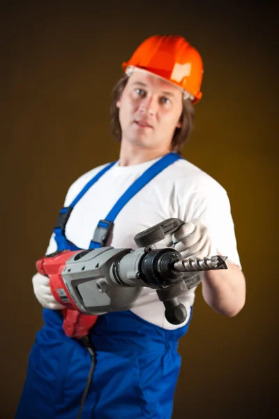 Worker holding a machine drill, focus on the drill — Stock Photo, Image