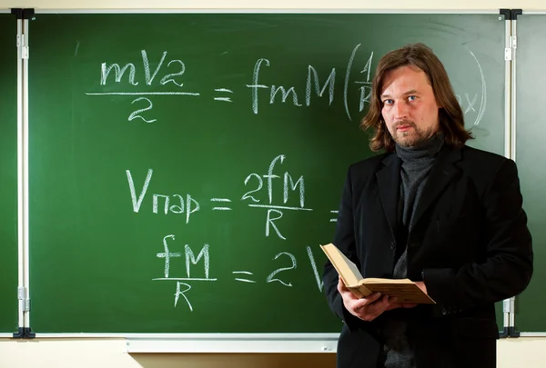 Math teacher against the blackboard — Stock Photo, Image