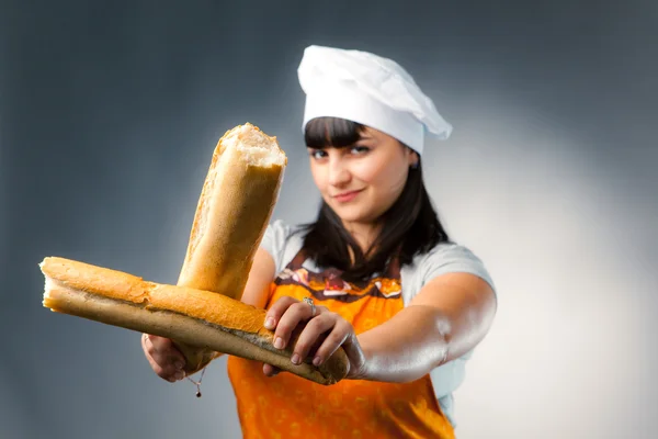 Woman cook crossing a french bread, focus on the bread — Stock Photo, Image