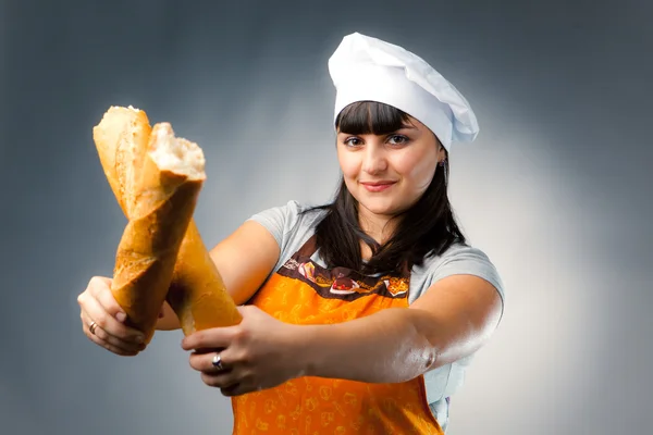 Woman cook crossing a french bread — Stock Photo, Image