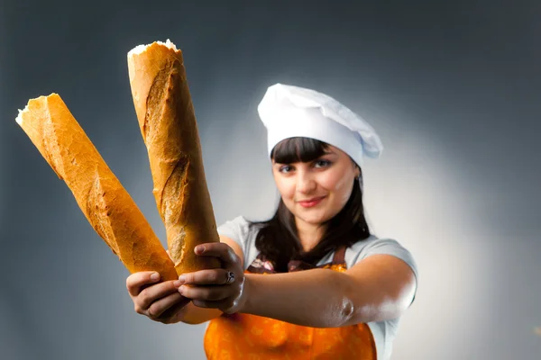 Woman cook holding breaked french bread, focus on the bread — Stock Photo, Image
