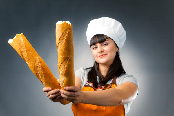 Woman cook holding breaked french bread, focus on the bread — Stock Photo, Image