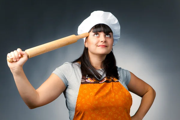 Thoughtful woman cook holding a rolling pin — Stock Photo, Image