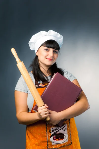 Woman cook with book and rolling pin — Stock Photo, Image