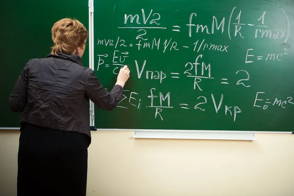 Math teacher writing formula on the blackboard — Stock Photo, Image