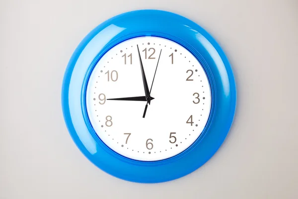 Blue office clock on grey wall — Stock Photo, Image
