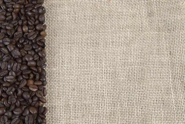 Pytlovina pozadí s kávová zrna. — Stock fotografie