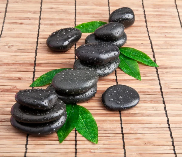 Blak spa stones with leaf and water drops. — Stock Photo, Image