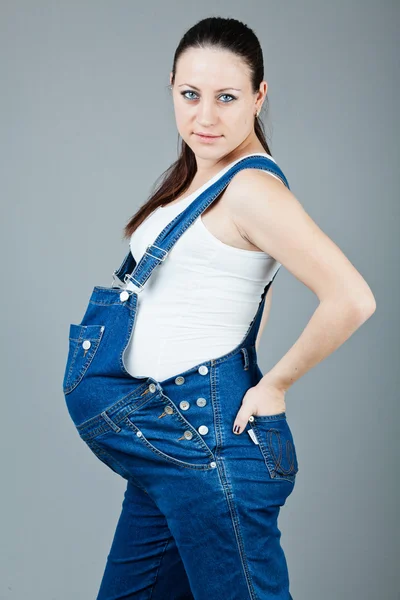 Portret van zwangere brunette vrouw op grijze achtergrond. — Stockfoto