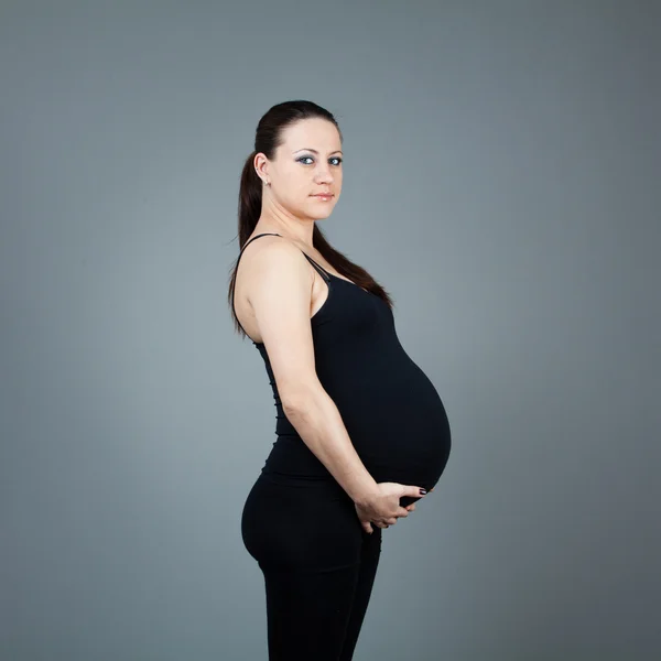 Portrait de femme brune enceinte sur fond gris . — Photo