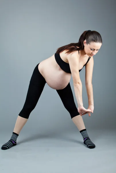 Portret van zwangere brunette vrouw op grijze achtergrond. — Stockfoto