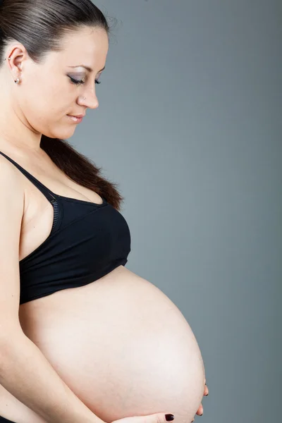Retrato de mujer morena embarazada sobre fondo gris . — Foto de Stock