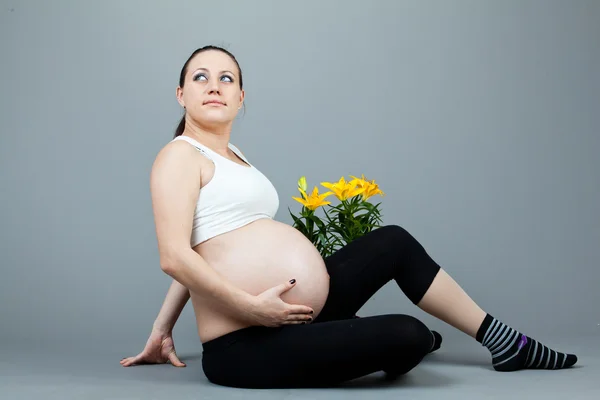 Портрет вагітної брюнетки на сірому фоні . — стокове фото