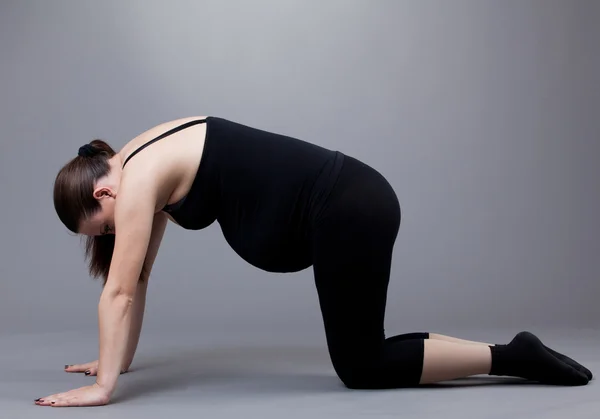 灰色の背景に体操をやっている妊娠中の女性. — ストック写真