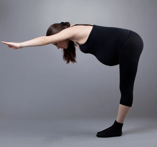 Mujer embarazada haciendo ejercicios de gimnasia sobre fondo gris . —  Fotos de Stock