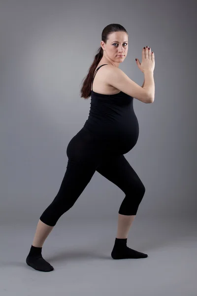 Hamile kadın gri arka plan üzerinde jimnastik egzersizleri yapıyor. — Stok fotoğraf