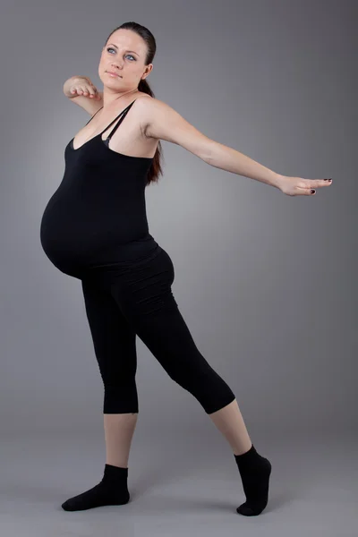 Mujer embarazada haciendo ejercicios de gimnasia sobre fondo gris . — Foto de Stock